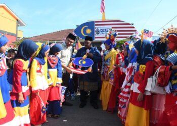 MOHD. Nadzri Jaafar (kanan) dan Hazalan Haron (kiri) bersama murid-murid di hadapan wau gergasi yang dihasilkan bersempena sambutan kemerderkaan peringkat sekolah itu di SK Kubang Gajah, Arau, Perlis hari ini.-UTUSAN/IZLIZAN OTHMAN