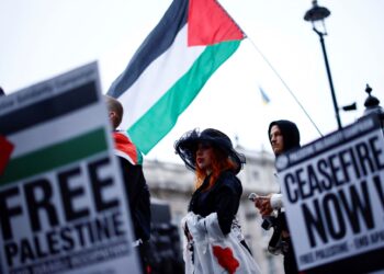 PENUNJUK perasaan mengibarkan bendera Palestin dan memegang sepanduk ketika himpunan di luar Downing Street di London, bagi mendesak gencatan senjata di Gaza.- AFP