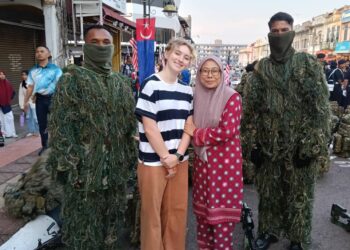 RACHEL Bailey dan Nurul Jannah Abu Bakar bergambar bersama anggota ATM ketika sambutan Hari Kebangsaan Malaysia di Dataran Segamat pagi ini