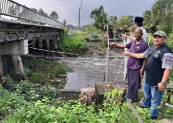 DAWIK Mohamad Ali (tengah) menunjukkan gumpalan rumput yang tersangkut di bawah Jambatan Sungai Ayer Baloi yang boleh merosakkan bot-bot nelayan di Pangkalan Nelayan Sungai Ayer Baloi, Pontian.