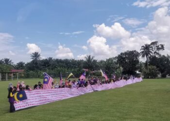 MURID dan guru SK Kampung Ayer Hitam di Teluk Intan menunjukkan kain rentang yang dicap dengan tapak tangan yang dihasilkan sempena Hari Kebangsaan. – UTUSAN/AIN SAFRE BIDIN