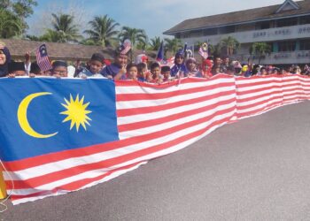 SEBAHAGIAN daripada murid dan guru bergambar bersama Jalur Gemilang gergasi yang dihasilkan sempena Hari Kebangsaan di  SK Ketengah II, Dungun, semalam. – UTUSAN/NIK NUR IZZATUL HAZWANI NIK ADNAN