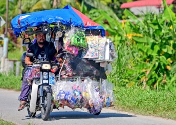 MUHAMMAD Akhir Abdul Aziz  menjaja pelbagai barangan makanan di atas motosikal roda tiga miliknya 
di Kampung Sungai Rengas, Kuala Terengganu semalam. – UTUSAN/PUQTRA HAIRRY ROSLI