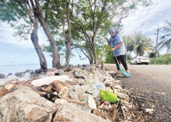 SALASIAH Hasan membersihkan kawasan jalan di hadapan rumahnya berikutan sampah yang melimpah di pesisir pantai dan jalan raya ekoran fenomena air pasang dan laut bergelora di Jalan Sungai Belati, Sanglang, Perlis, semalam. – UTUSAN/ASYRAF MUHAMMAD