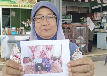 FUZIAH Morad menunjukkan gambar kenangan dua arwah abangnya, Zainol dan Abdullah yang meninggal dunia dalam kejadian kepala air tiga tahun lalu ketika ditemui di Yan, Kedah, semalam.