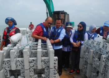 KETUA Pegawai Teknologi SIRIM Industrial Research, Ir. Dr. Muhammad Izzal Ismail (dua dari kanan) memberi penerangan kepada Fairul Nizam Roslan sewaktu meninjau proses melabuhkan 20 unit tukun inovasi di perairan Telok Mas, Melaka. - UTUSAN/AMRAN MULUP