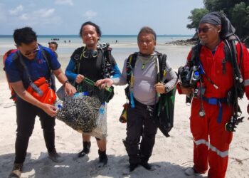 SEBAHAGIAN penyelam menunjukkan antara sampah dan pukat hantu yang berjaya dikutip di dasar laut sempena Program Pemuliharaan Biodiversiti Marin Port Dickson di Pantai Tanjung Biru, Port Dickson semalam.-UTUSAN/MOHD. SHAHJEHAN MAAMIN.