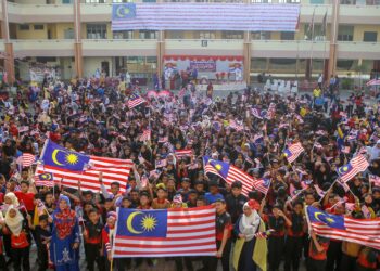 MURID SK Darulaman Heights mengibarkan bendera berlatarbelakangkan Jalur Gemilang gergasi berukuran 20 meter panjang yang dicat menggunakan 1,240 tapak tangan warga sekolah itu di Jitra, Kubang Pasu. - UTUSAN/ SHAHIR NOORDIN