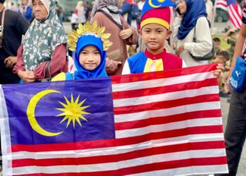 MUHAMAD Haziq Muhamad Hamka (kanan) bersama  adiknya, Nuranis Aqilah berbusana tema Jalur Gemilang ketika menyaksikan perarakan Hari Kebangsaan Ke-67 Peringkat Kedah di Dataran Medan Bandar, Alor Setar semalam.