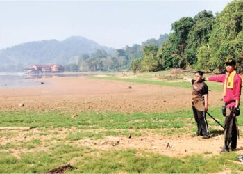 KAKITANGAN Yayasan Pulau Orang Utan Tasik Bukit Merah menunjukkan keadaan tasik yang kering akibat cuaca panas. – UTUSAN/WAT KAMAL ABAS