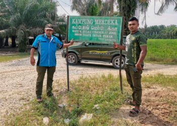 PENDUDUK menunjukkan papan tanda Kampung Merdeka ketika tinjauan Utusan Malaysia di kampung tersebut di Teluk Intan. – UTUSAN/AIN SAFRE BIDIN