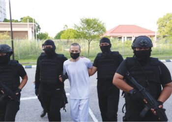 ANGGOTA polis membawa Nik Mohd. Shalahuddin Zakaria semasa prosiding sebutan semula kes di Mahkamah Sesyen Kota Bharu, Kelantan, semalam. – UTUSAN/ROSALWANI CHE SOH.