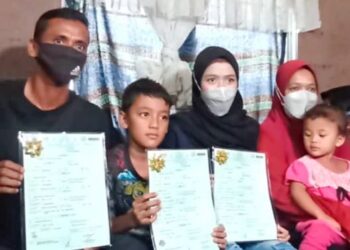 NOR Ashikin Hariandi (dua dari kanan) menunjukkan sijil kelahiran yang diterima bersama dua adiknya di Malim Nawar, Kampar, Perak, hari ini. - UTUSAN/MEGAT LUTFI MEGAT RAHIM