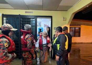 ANGGOTA penyelamat membantu seorang warga emas yang terjejas akibat banjir kilat yang melanda Masjid Tanah, Alor Gajah, Melaka.