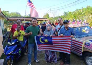 ABDUL Latip Alias (kanan) bersama peserta konvoi menyampaikan Jalur Gemilang kepada salah sebuah rumah penduduk sempena Program Semarak Merdeka di Chengkau, Rembau hari ini.-UTUSAN/NOR AINNA HAMZAH.