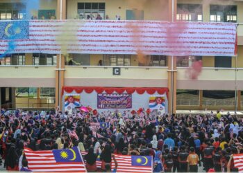 MURID SK Darulaman Heights mengibarkan bendera berlatarbelakangkan Jalur Gemilang gergasi berukuran 20 meter panjang yang dicat menggunakan 1,240 tapak tangan warga sekolah itu di Jitra, Kubang Pasu. - UTUSAN/ SHAHIR NOORDIN