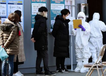 INDIVIDU disyaki dijangkiti Covid-19 menunggu giliran untuk menjalani ujian saringan di pusat perubatan di Daegu, Korea Selatan, pada 20 Februari 2020.- AGENSI