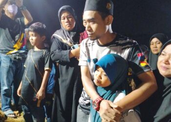 YUSOF Mokhtar kelihatan sebak sambil memeluk anak sulungnya semasa menghadiri pengebumian jenazah isterinya di perkuburan Islam Kubur Besar Bandar Pasir Mas, Pasir Mas, Kelantan. - UTUSAN/ROHANA ISMAIL.