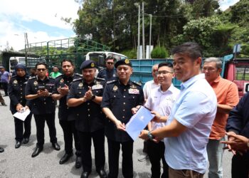 AEDY Fadly Ramli (dua dari kanan) menyerahkan dokumen pengurangan kadar bayaran fi LKM bagi kenderaan 'de-controlled' CH kepada Lau Sai Hoong di Cameron Highlands hari ini. - UTUSAN