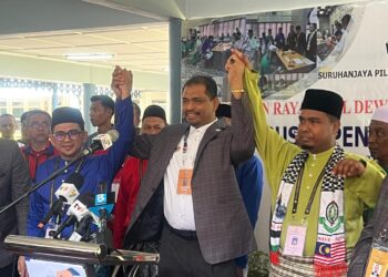 NIK Raisnan Daud (tengah) mengangkat tangan calon BN Mohd. Azmawi Fikri Abdul Ghani (kiri) dan PN Mohd. Rizwadi Ismail (kanan) selepas selesai proses penamaan calon PRK Nenggiri di Dewan Perdana, Kompleks Perdana, Majlis Daerah Gua Musang, Kelantan hari ini. -UTUSAN/AIMUNI TUAN LAH.