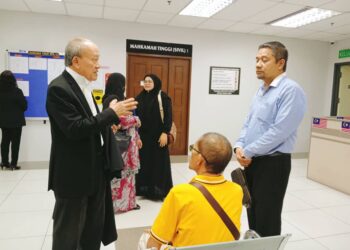 IDHAM Wazir (baju biru) mendengar penerangan peguamnya, Kamaruddin Ahmad sebelum memasuki kamar Mahkamah Tinggi Sivil, Johor Bahru.