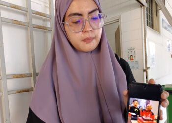 FARHANA Omar menunjukkan gambar Allahyarham Abu Zaini Ibrahim ketika ditemui  di Unit Perubatan Forensik, Hospital Tuanku Ampuan Najihah (HTAN), Kuala Pilah. – UTUSAN/NOR AINNA HAMZAH