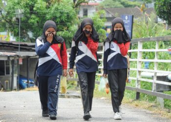 PELAJAR sekolah menutup hidung ketika berjalan berhampiran Sungai Pandan yang berbau  di Kampung Melayu Pandan, Johor Bahru. UTUSAN/RAJA JAAFAR ALI