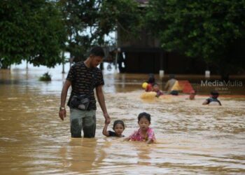 SEORANG penduduk membawa anak-anaknya mengharungi banjir di Kampung Kubang Betong, Changlun, Kubang Pasu, Kedah. - UTUSAN/ SHAHIR NOORDIN