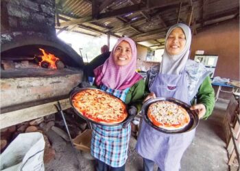 NUR Faizah Jaafar (kiri) bersama madunya, Sarinah Ismail  menunjukkan piza yang dijual di kedai mereka di Kampung Lubuk Kawah, Besut, semalam. – UTUSAN/WAN ZURATIKAH IFFAH WAN ZULKIFLI