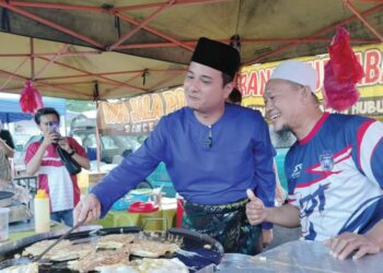 SYED HUSSIEN Syed Abdullah membantu seorang peniaga menyediakan  martabak ketika tinjauan di Pasar Malam Bukit Ayam 
di Kluang, Johor malam kelmarin.