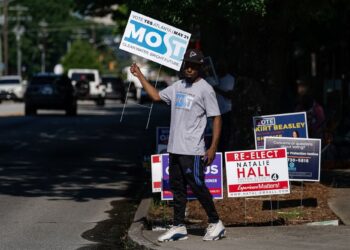 SEORANG lelaki memegang poster kempen di luar lokasi mengundi di Atlanta, Georgia.-AFP