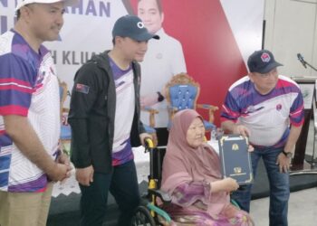 MOHD JAFNI Md. Shukor (kiri) mengiringi Onn Hafiz Ghazi menyampaikan geran hak milik tanah kepada seorang penerima di Balai Raya Kampung Bentong Luar, Kluang, Johor.