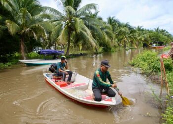 PENDUDUK Kampung Alor Ali, Ahmad Shafie bersama rakannya mengambil inisiatif meronda menggunakan bot di sekitar kampung yang menempatkan kira-kira 500 buah rumah yang dilanda banjir termenung di Pendang. - UTUSAN/ SHAHIR NOORDIN