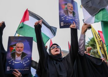 RAKYAT Iran mengibarkan bendera Palestin dan memegang potret pemimpin Hamas, Ismail Haniyeh yang terbunuh, di dataran Palestin, ibu negara Teheran pada 31 Julai lepas.- AFP