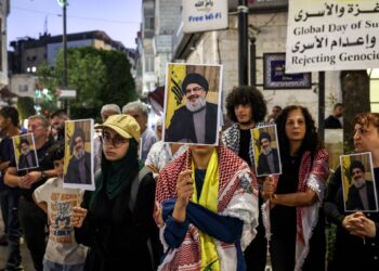 PENUNJUK perasaan berdiri sambil memegang sepanduk wajah Hassan Nasrallah ketika protes di bandar Ramallah di Tebing Barat.-AFP