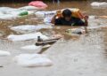 SEORANG lelaki memikul seguni tepung sambil meredah banjir selepas Sungai Bagmati melimpah ekoran hujan monsun di Kathmandu, kelmarin.- AFP