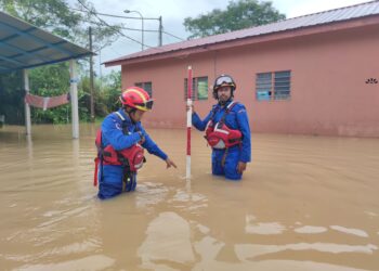 DUA anggota APM mengukur paras semasa air di salah sebuah kampung yang dilanda banjir di Kubang Pasu. - IHSAN APM