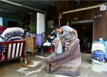 MOHD. Izham Abdul Manaf membersihkan perabot dan barangan di rumahnya di Kampung Suka Menanti, Alor Setar, yang rosak selepas ditenggelami banjir. – UTUSAN/ SHAHIR NOORDIN