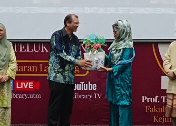 ROSLI Md. Illias (dua dari kiri) menyampaikan cenderamata kepada Siti Zainon Ismail sambil diperhatikan oleh Nor Asikin Mohamad (kiri) pada Majlis Pelancaran Laman Baca Celik Hati: Projek Buku Braille di UTM, Johor Bahru.