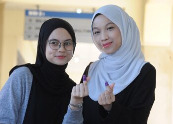 DUA beradik,Ilia Insyirah Mahasan (kiri) dan  kakaknya, Irfa Nurhani menunjukkan calitan dakwat pada jari selepas mereka mengundi di SMK Seri Perdana, KluanG.