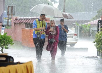 SEORANG petugas SPR memayungi seorang pengundi warga emas dalam hujan lebat menuju ke pusat pengundian  di Sekolah Agama Gunung Lambak, Kluang.