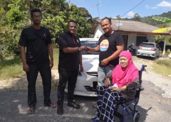 SYED Alwi Syed Jaafar (dua dari kiri) menyerahkan kunci kereta kepada Khuzaifah di Kampung Sungai Mahanh, Nilai, Seremban untuk kegunaan mendapatkan rawatan susulan buat ibu pemuda tersebut.-UTUSAN /NUR SHARIEZA ISMAIL.