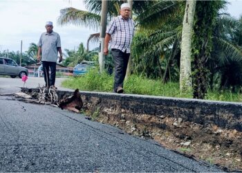 ABDUL Yunus Jamahri  (kiri) menunjukkan keadaan jalan yang mendap di Kampung Sungai Burung Kuala Kurau di Parit Buntar. - UTUSAN/WAT KAMAL ABAS