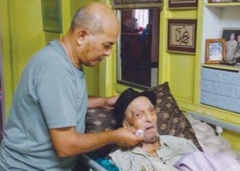 ROSLEE Abd. Rashid mengelap muka bapanya, Mat Sentol di rumah mereka di Larkin, Johor Bahru.