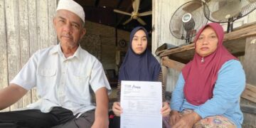 WAN Nur’alyaa Syaza Awang (tengah) bersama ibu bapanya menunjukkan slip tawaran pengajian USM yang diterimanya tetapi masalah kewangan menjadi kekangan kepadanya di Tok Bali, Pasir Puteh, Kelantan, baru-baru ini. – UTUSAN/TOREK SULONG