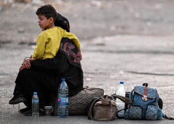 SEORANG wanita memangku anaknya berhampiran beg pakaian mereka di Jdeidat Yabus di sempadan Syria dengan Lubnan.-AFP