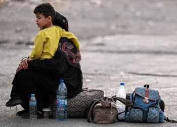 SEORANG wanita memangku anaknya berhampiran beg pakaian mereka di Jdeidat Yabus di sempadan Syria dengan Lubnan.-AFP