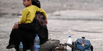 SEORANG wanita memangku anaknya berhampiran beg pakaian mereka di Jdeidat Yabus di sempadan Syria dengan Lubnan.-AFP