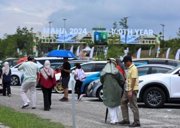 Pengunjung sanggup berjalan kaki dan berpanas dari tempat meletak kereta yang terletak jauh dari tapak pameran kerana bimbang kawasan meletak kenderaan di bahagian dalam penuh. - UTUSAN/AMIR KHALID