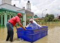 Warga emas menggunakan tong sebagai sampan mengharung air banjir di Masjid Tuan Hussin, Titi Gajah bagi menunaikan Solat Jumaat. UTUSAN/ SHAHIR NOORDIN